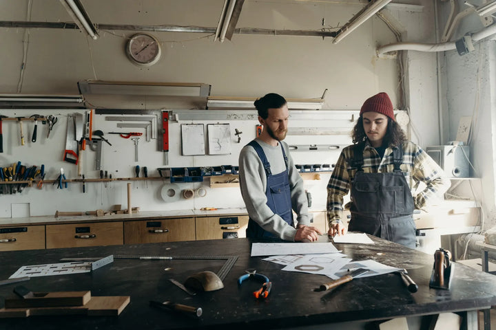 Twee vakmensen overleggen aan een werkbank in de werkplaats