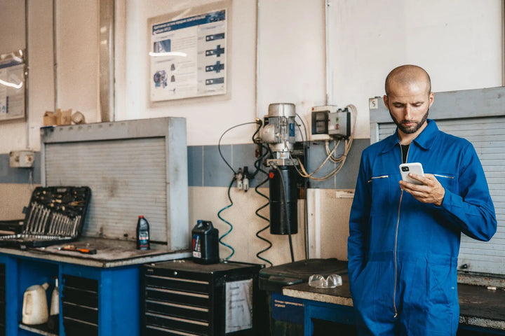 Vakman bedient zijn telefoon in een werkplaats